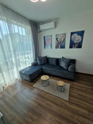 a living room with a blue couch and two tables at Апартамент СаMи in Burgas City