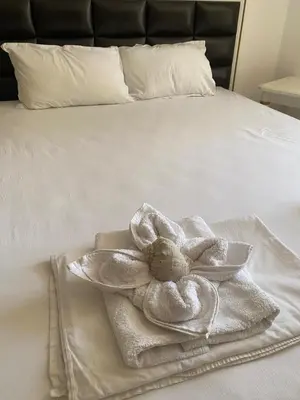 a white towel with a flower on a bed at Penthouse Happy Moments 2 in Sunny Beach