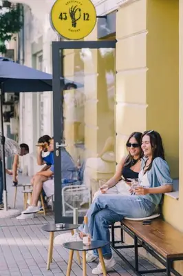 two women sitting on a bench outside a building at Varna Central Ohrid 2bdr Apartment in Varna City
