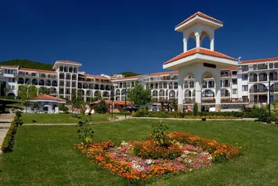 a large building with a clock tower in a park at Kambani Arnel Apartment , Marina in Sveti Vlas
