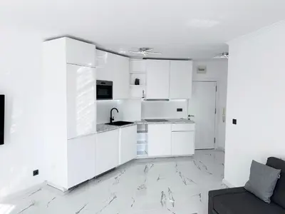 a white kitchen with white cabinets and a couch at Admiral Plaza Apartment , Large swimming pool , 5 min walking to the beach in Sunny Beach