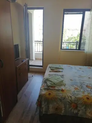 a bedroom with a bed and a dresser and two windows at Созопол Дриймс FSM Апартамент in Sozopol
