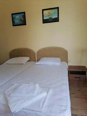 a white bed in a bedroom with two pictures on the wall at Созопол Дриймс FSM Апартамент in Sozopol