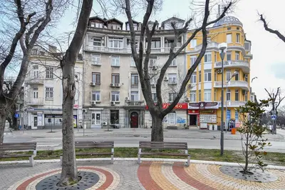 a park with two benches in front of a building at Budget central next to sea garden and beach in Varna City
