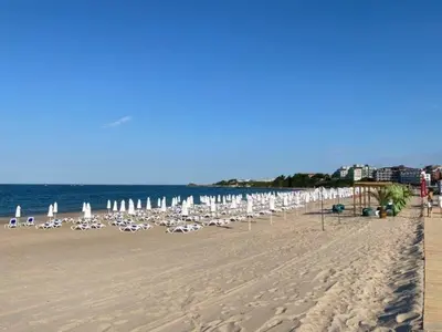 a beach with chairs and umbrellas and the ocean at Студио Симона 4 - първа линия море in Lozenets