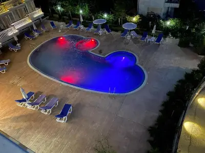 an empty swimming pool with chairs and tables at Студио Симона 4 - първа линия море in Lozenets