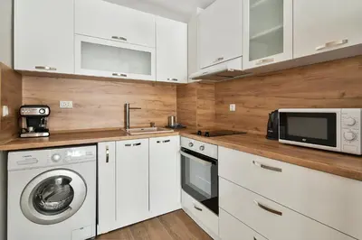 a kitchen with white cabinets and a washer and dryer at Top location flats in Varna in Varna City