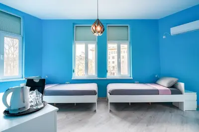a blue room with two beds and two windows at ПАЦО in Burgas City