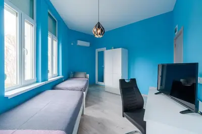 a room with blue walls and beds and a tv at ПАЦО in Burgas City