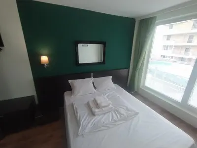 a bedroom with a white bed with a green wall at Sunny place in Sveti Vlas
