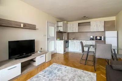 a living room with a flat screen tv and a kitchen at Central train station Flat with port view in Varna City