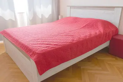 a bed with a red blanket on top of it at Central train station Flat with port view in Varna City