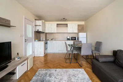 a living room with a couch and a table and a kitchen at Central train station Flat with port view in Varna City