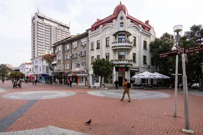 a woman walking down a street in front of a building at Top location in center and paid parking in Varna City