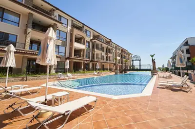 a swimming pool with chairs and umbrellas next to a building at M1 Pool and Beach View Apartment in Burgas City