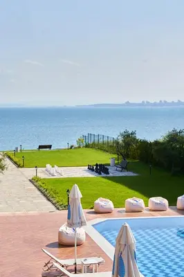 a swimming pool with two umbrellas next to the ocean at M1 Pool and Beach View Apartment in Burgas City