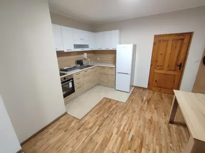 an empty kitchen with a white refrigerator and wooden floors at Longoz in Bliznatsi