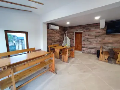 a dining room with wooden benches and a tv at Longoz in Bliznatsi