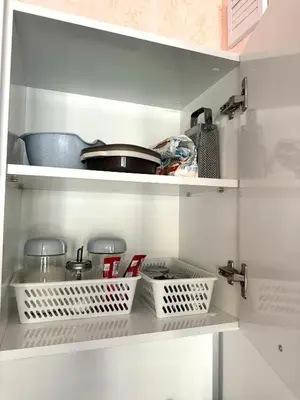 a kitchen with white shelves with pans and utensils at Студия Sea Breeze in Sveti Vlas