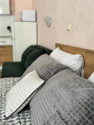 a bed with a gray comforter and a pillow on it at Студия Sea Breeze in Sveti Vlas