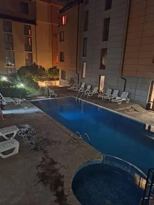 a large swimming pool with chairs and a building at Студия Sea Breeze in Sveti Vlas