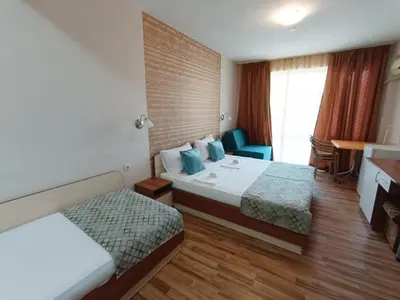 a hotel room with two beds and a desk at Семеен Хотел Детелини in Primorsko