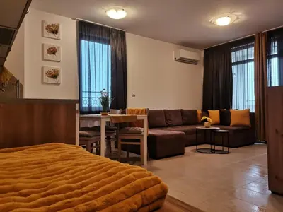 a living room with a couch and a table at Апартамент Orange в местност Каваци, Созопол in Sozopol