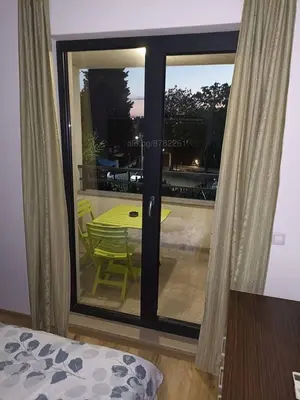 a room with a glass door with a table and a view at Apartament Topalov in Burgas City