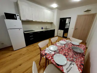 a kitchen with a table and chairs and a kitchen with white appliances at Apartament Topalov in Burgas City