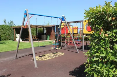 a playground with two swings and a slide at Atia Resort in Chernomorets