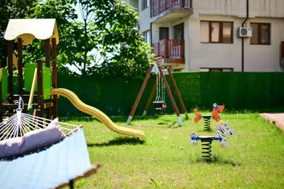 a playground with a slide and swings in a yard at Kristin Palace in Obzor