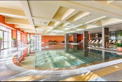 a large swimming pool in a hotel lobby at Reina Apart Barcelo Beach in Sunny Beach