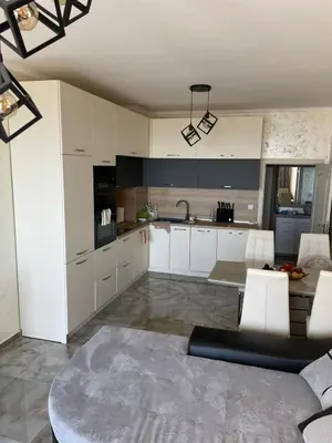 a kitchen with white cabinets and a table and chairs at Luxury Penthouse Apartments at Valencia Gardens in Burgas City