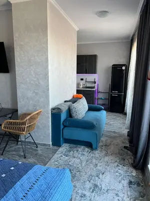 a living room with a blue couch and a kitchen at Luxury Penthouse Apartments at Valencia Gardens in Burgas City