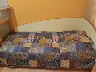 a bed in a room with a quilt on it at ПРИНЦЕС in Burgas City