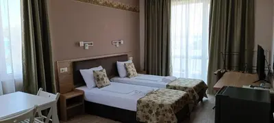 a hotel room with two beds and a television at Апартаменти Детелини in Primorsko