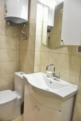 a bathroom with a sink and a toilet and a mirror at Trimaya apartment - comfort in the top city center in Varna City