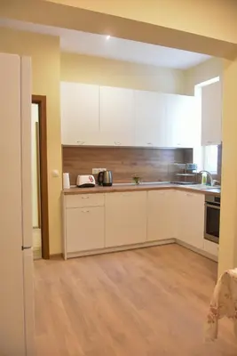 a kitchen with white cabinets and a wooden floor at Trimaya apartment - comfort in the top city center in Varna City