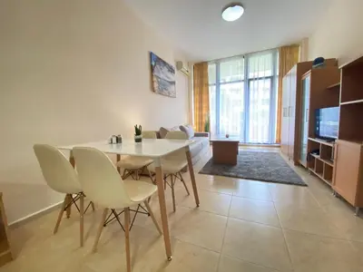a dining room with a white table and chairs at Trakia Plaza Apartament Sunny Beach in Sunny Beach