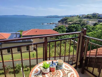 a table on a balcony with a view of the ocean at Созополски Рай in Sozopol