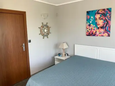a bedroom with a bed and a painting on the wall at Nessebar panoramic apartment in Nesebar