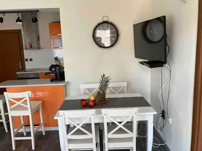 a kitchen with a table and chairs and a clock on the wall at Nessebar panoramic apartment in Nesebar
