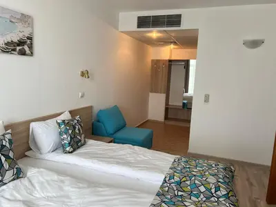 a bedroom with a bed and a blue chair at Royal Marina Beach in Chernomorets
