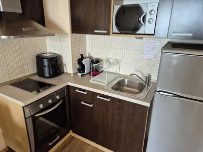 a small kitchen with a sink and a microwave at Апартамент Б306 в Обзор Бийч Резорт на първа линия с перфектен изглед към плажа! in Obzor