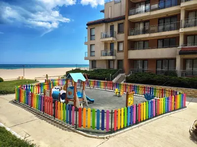 a playground in front of a building next to the beach at Апартамент Б306 в Обзор Бийч Резорт на първа линия с перфектен изглед към плажа! in Obzor