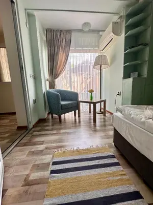 a living room with a bed and a chair and a window at Green Central Apartment in Varna City