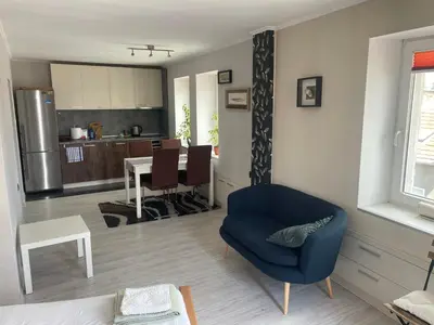 a living room with a blue chair and a kitchen at Studio flat in the heart of Burgas in Burgas City